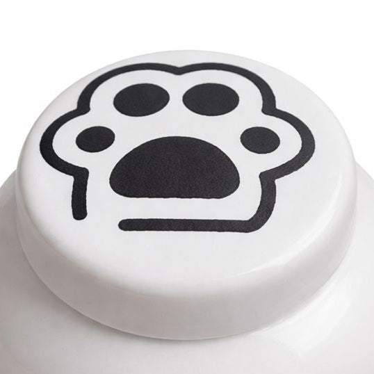 Witte keramische kattenurn met zwarte pootafdruk op het deksel